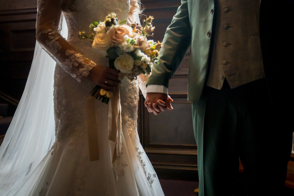 Bride and groom holding hands, wedding bouquet visible.