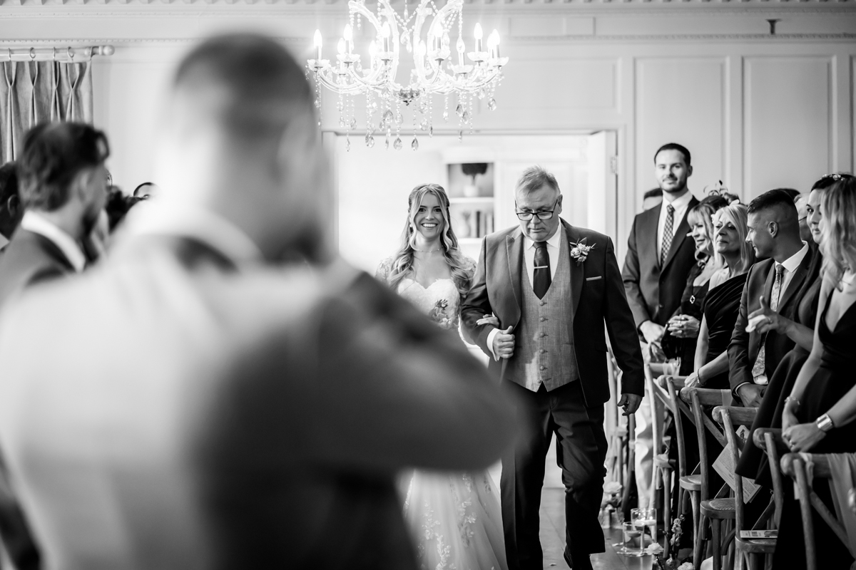 Bride walking down aisle with father, wedding ceremony.