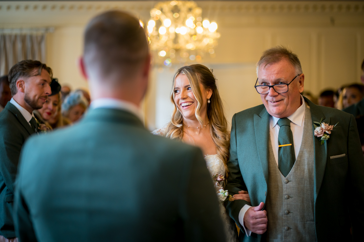 Smiling bride and father walking down the aisle.