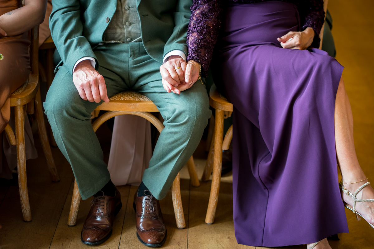 Elegantly dressed couple holding hands at event.