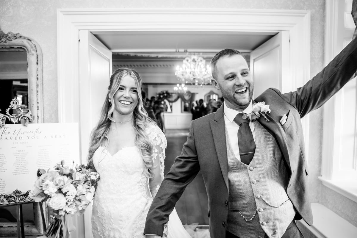 Happy couple at wedding entrance, smiling broadly.