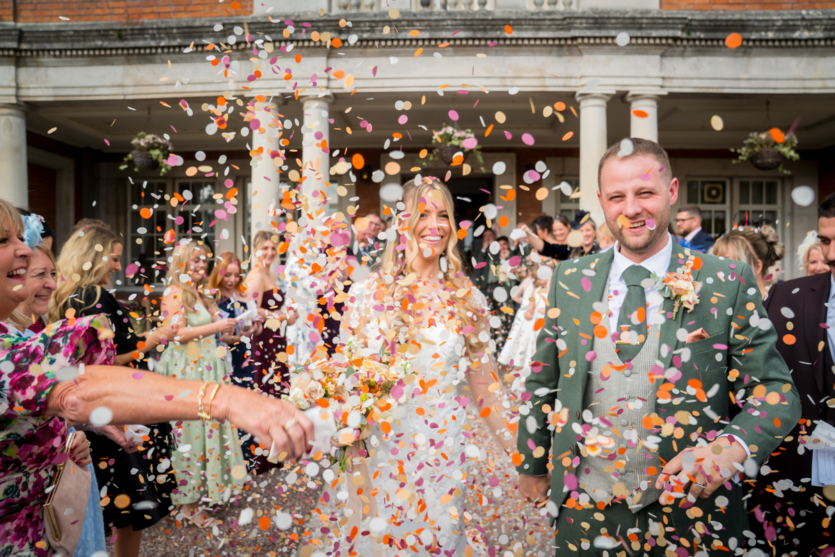 Newlyweds smiling under colourful confetti shower