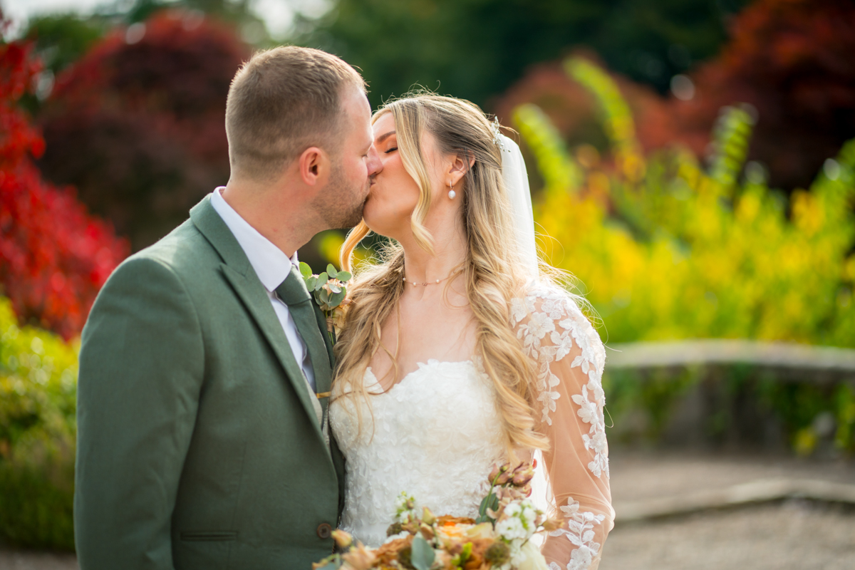 Bride and groom kissing in garden