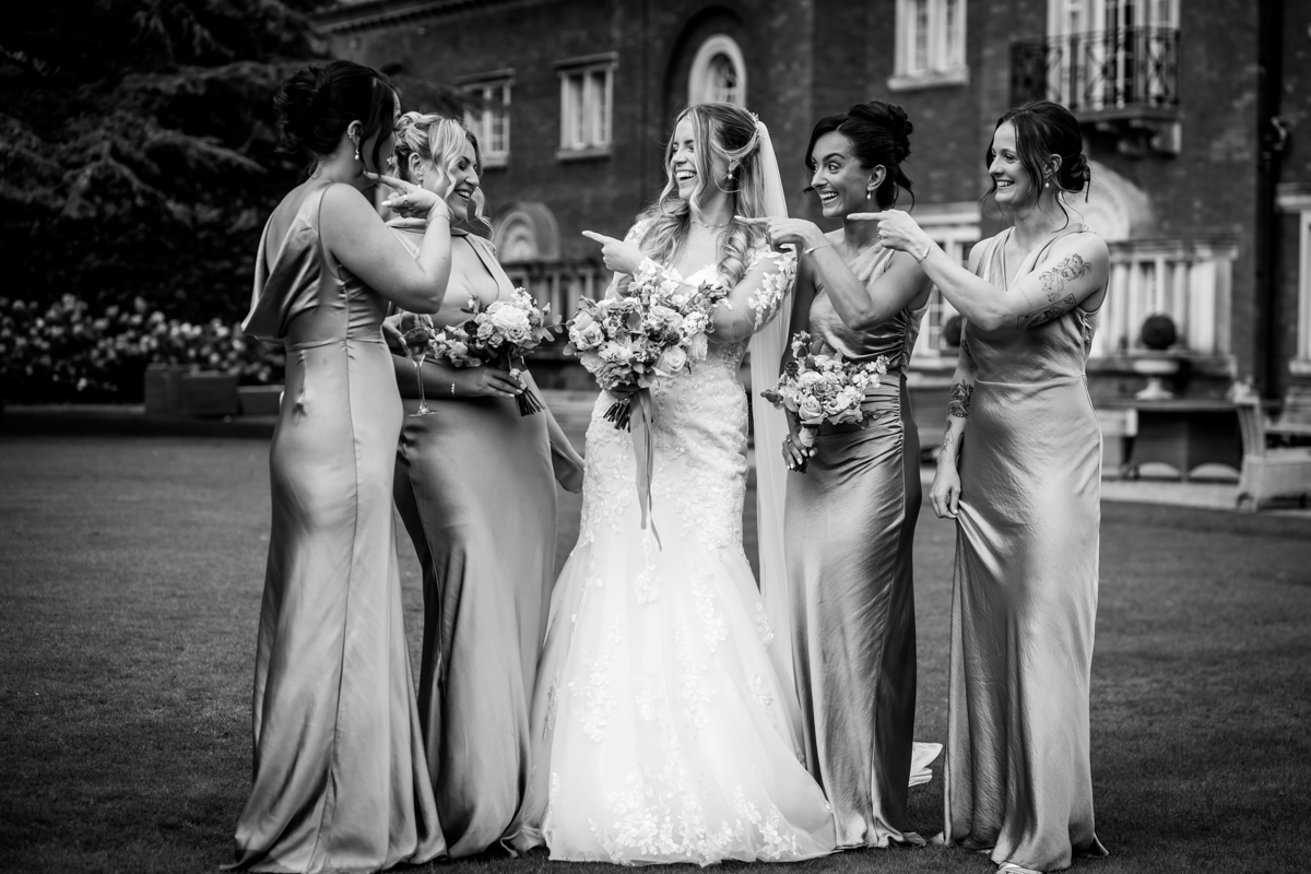 Bride and bridesmaids laughing and pointing.