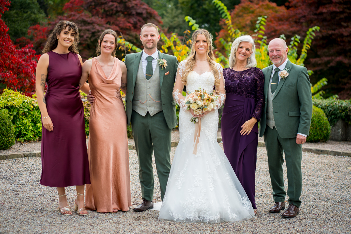 Wedding party posing for a group photo outside.