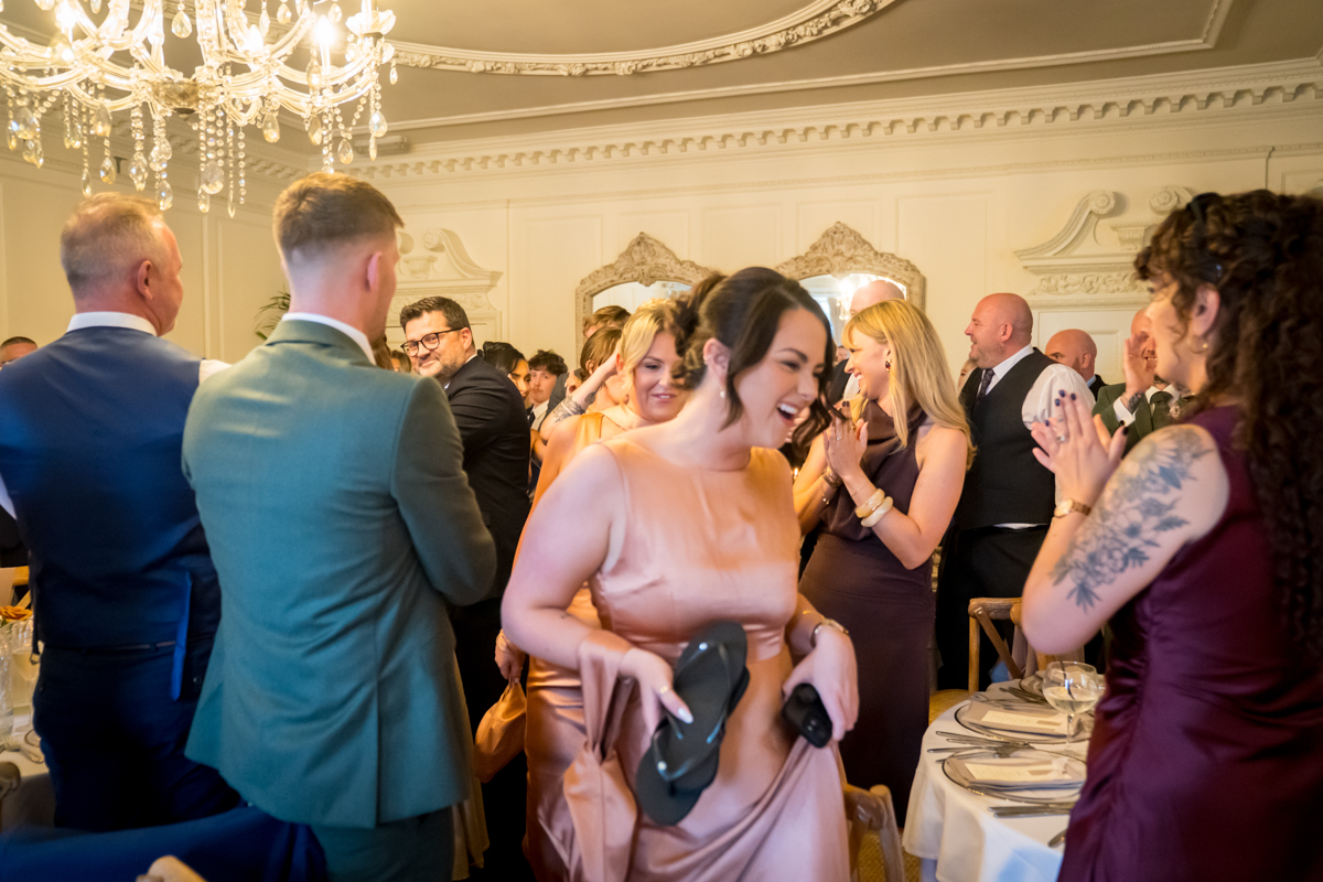 Joyful wedding celebration with guests clapping inside venue.