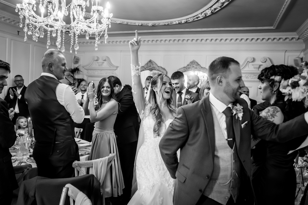 Celebratory wedding dance with happy guests applauding.