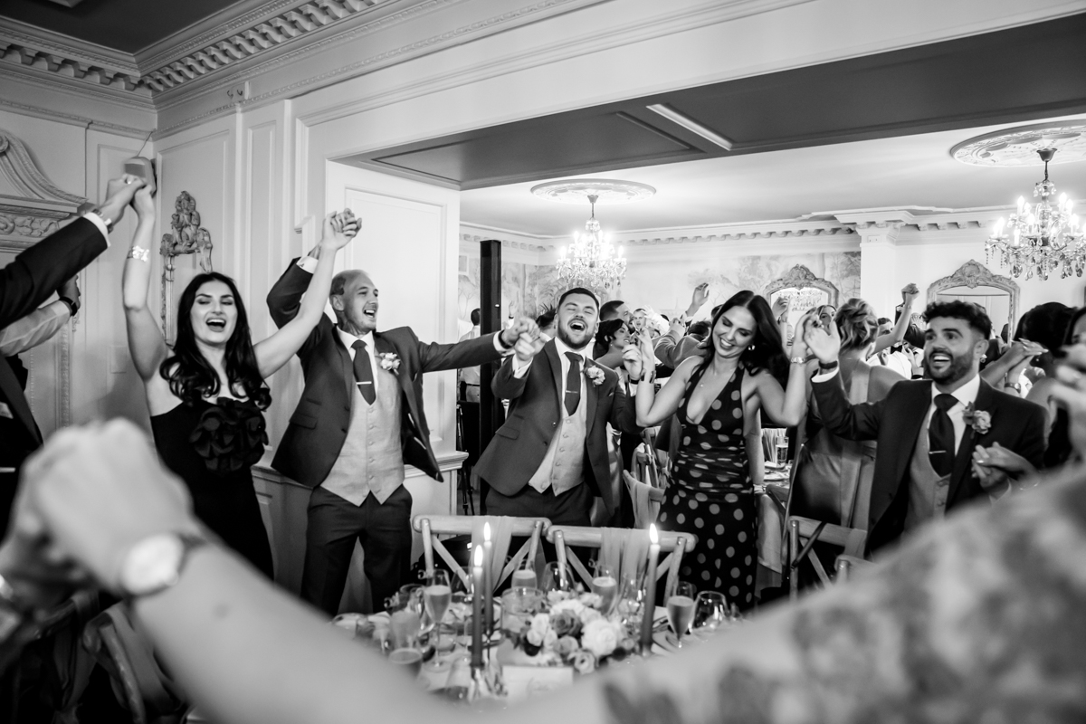 Guests celebrate with raised hands at a wedding.