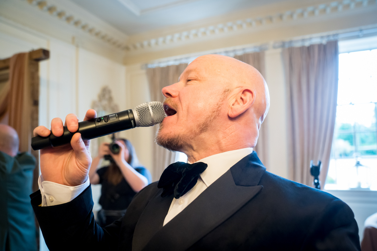 Man in suit singing with microphone indoors.