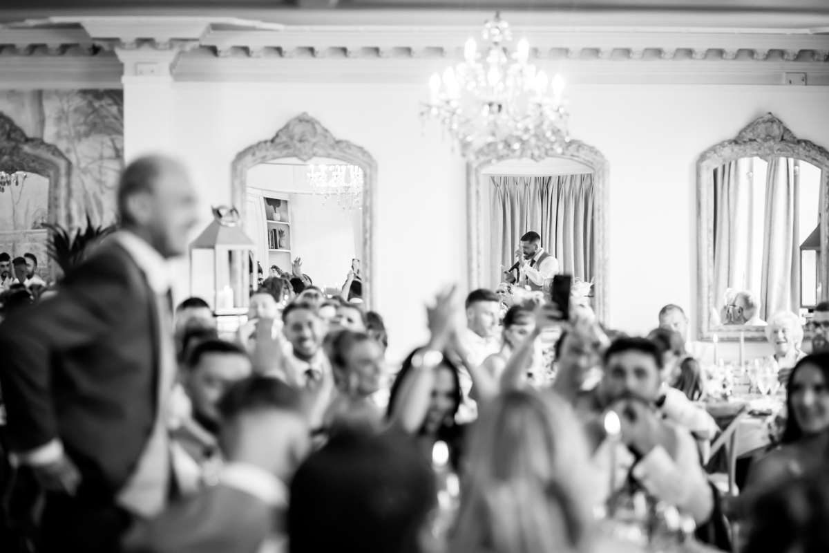 Wedding speech in elegant reception room with chandeliers.