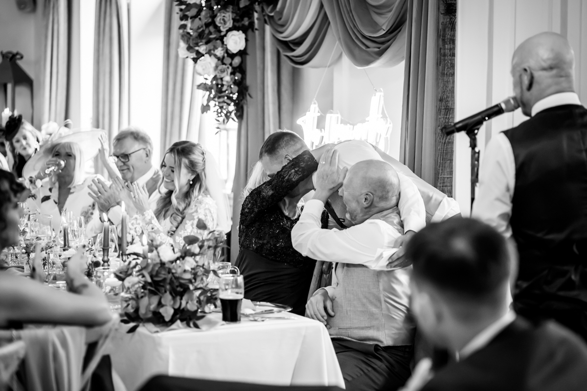 Wedding guests laughing and clapping during speech.