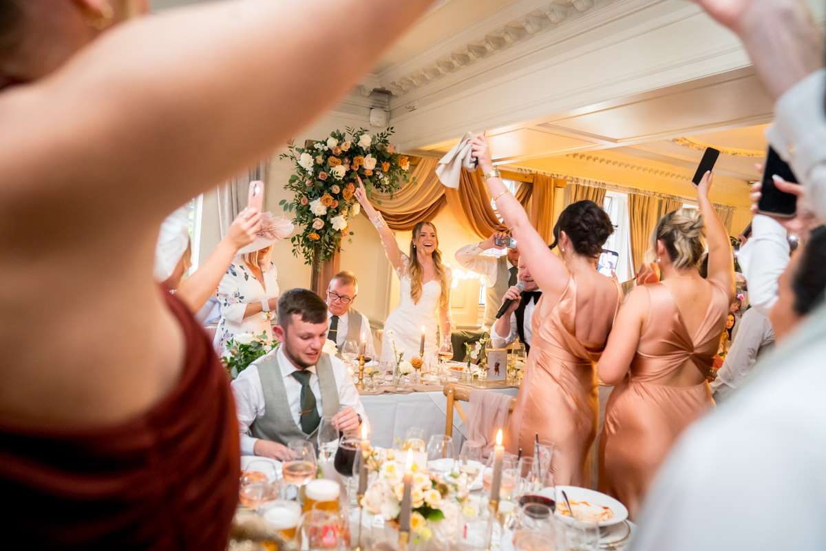 Bride celebrating at lively wedding reception.