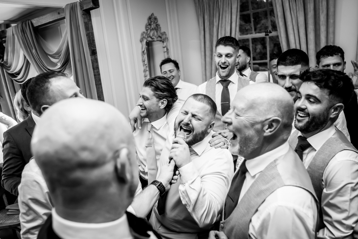 Group of men singing and laughing at party.