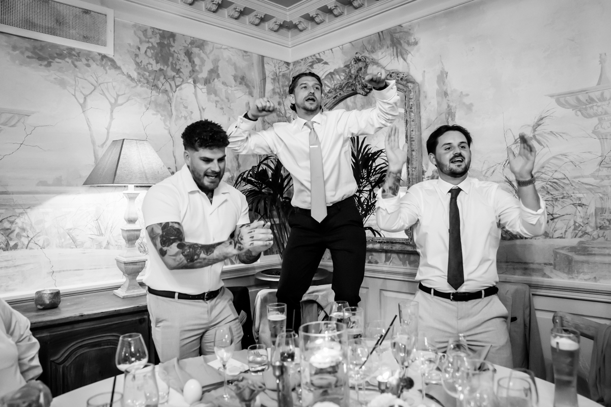 Three men celebrating joyfully at a dinner party.