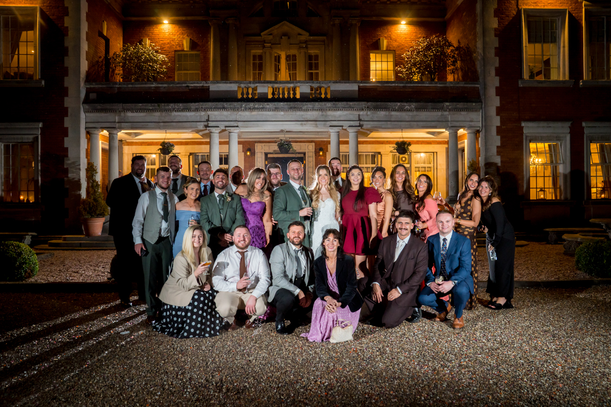 Group posing outside elegant building at night.
