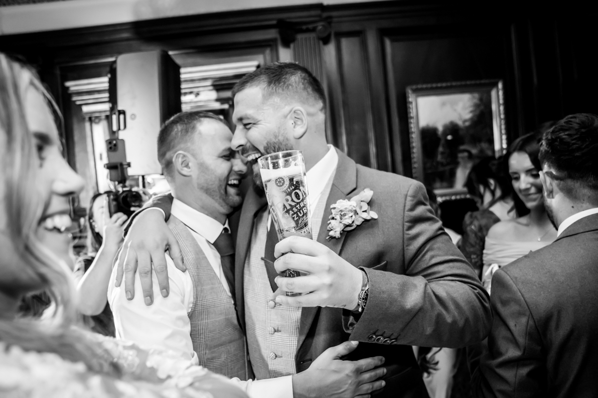 Two men celebrating and laughing at a wedding.