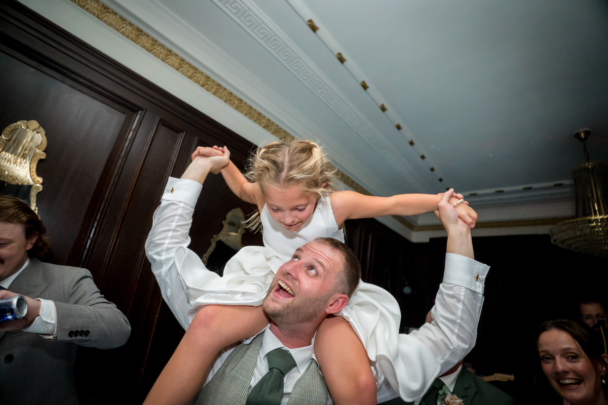 Man carrying child on shoulders, both smiling happily.