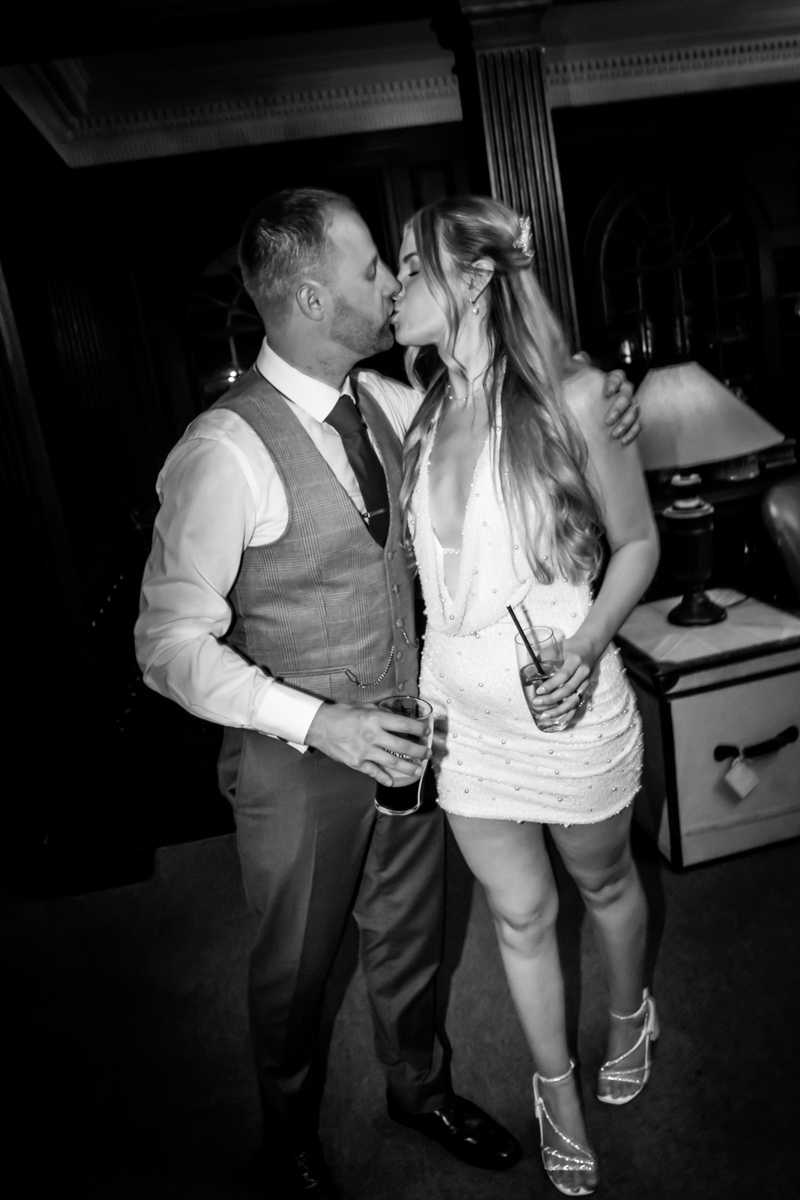 Couple kissing at formal event in evening attire.