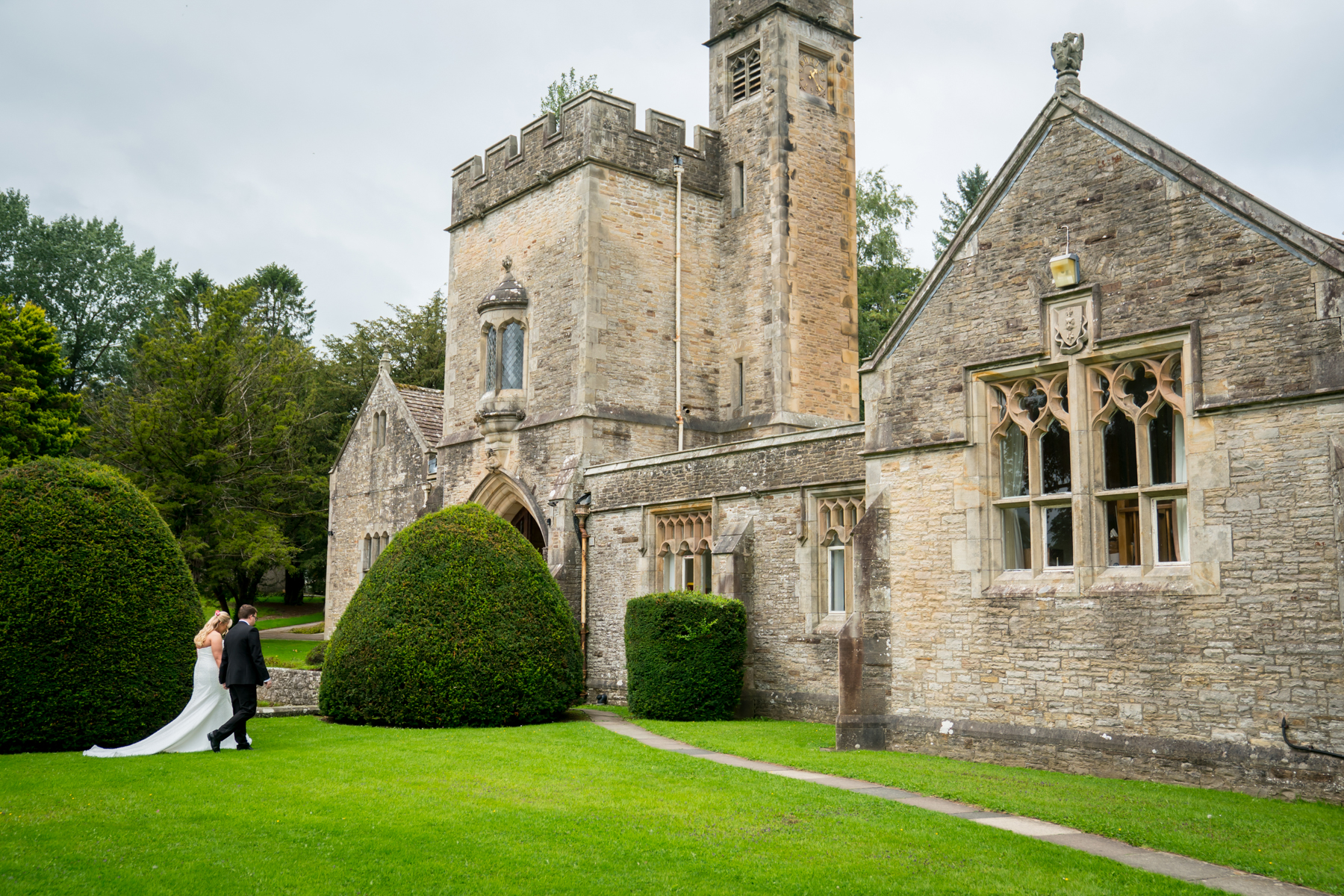 Bride and groom walking by historic stone building