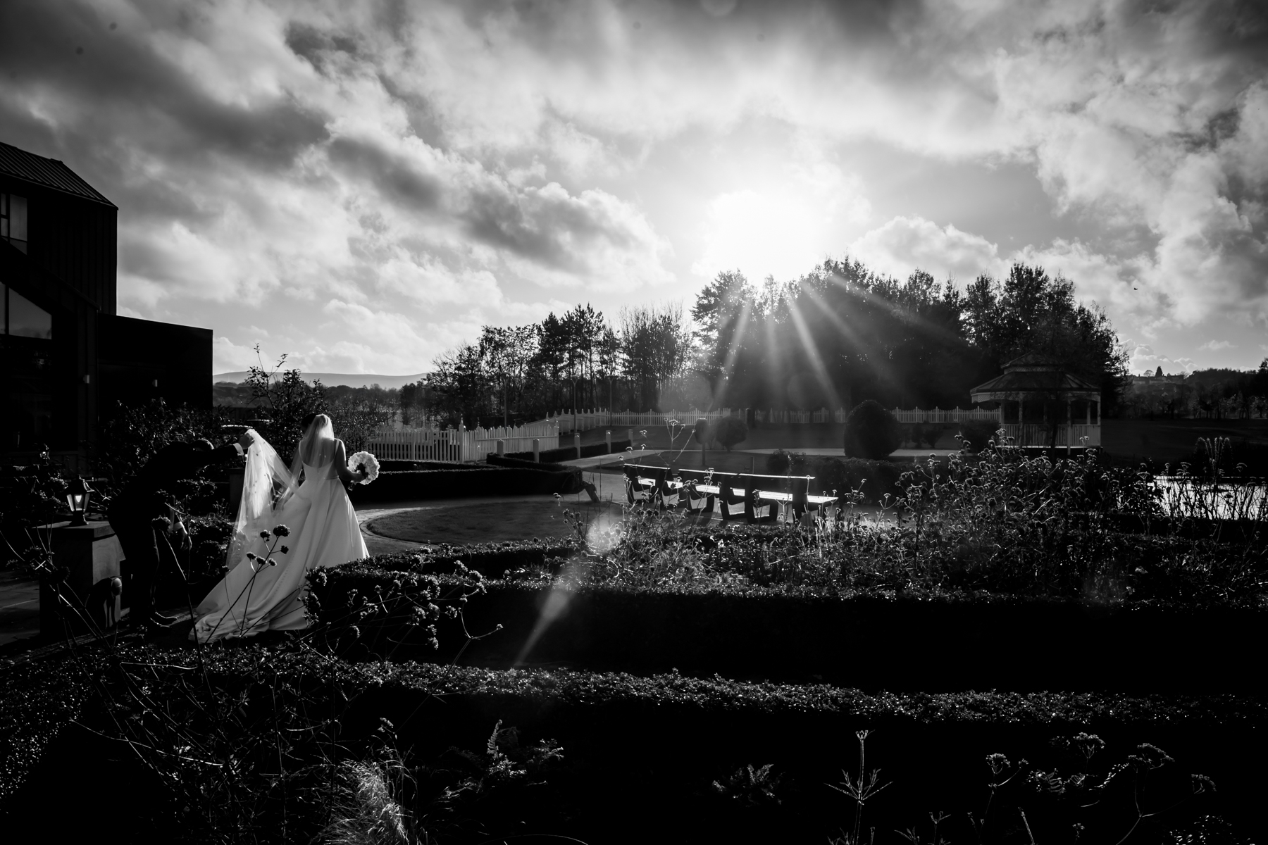 Bride walking outdoors in garden, black and white