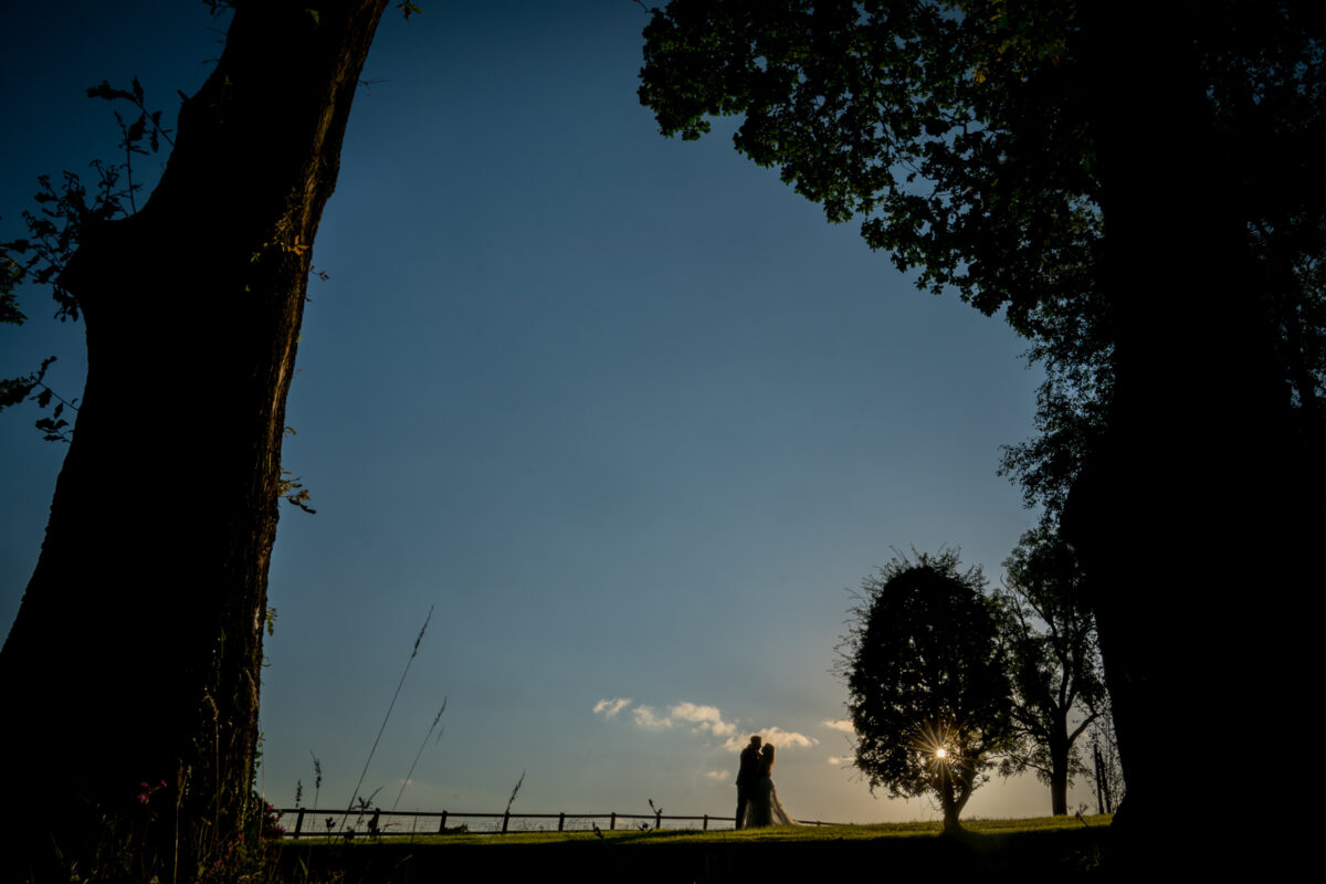 Silhouette of couple embracing under a twilight sky.