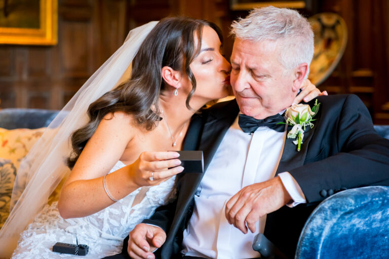 Bride kissing older man at wedding ceremony.