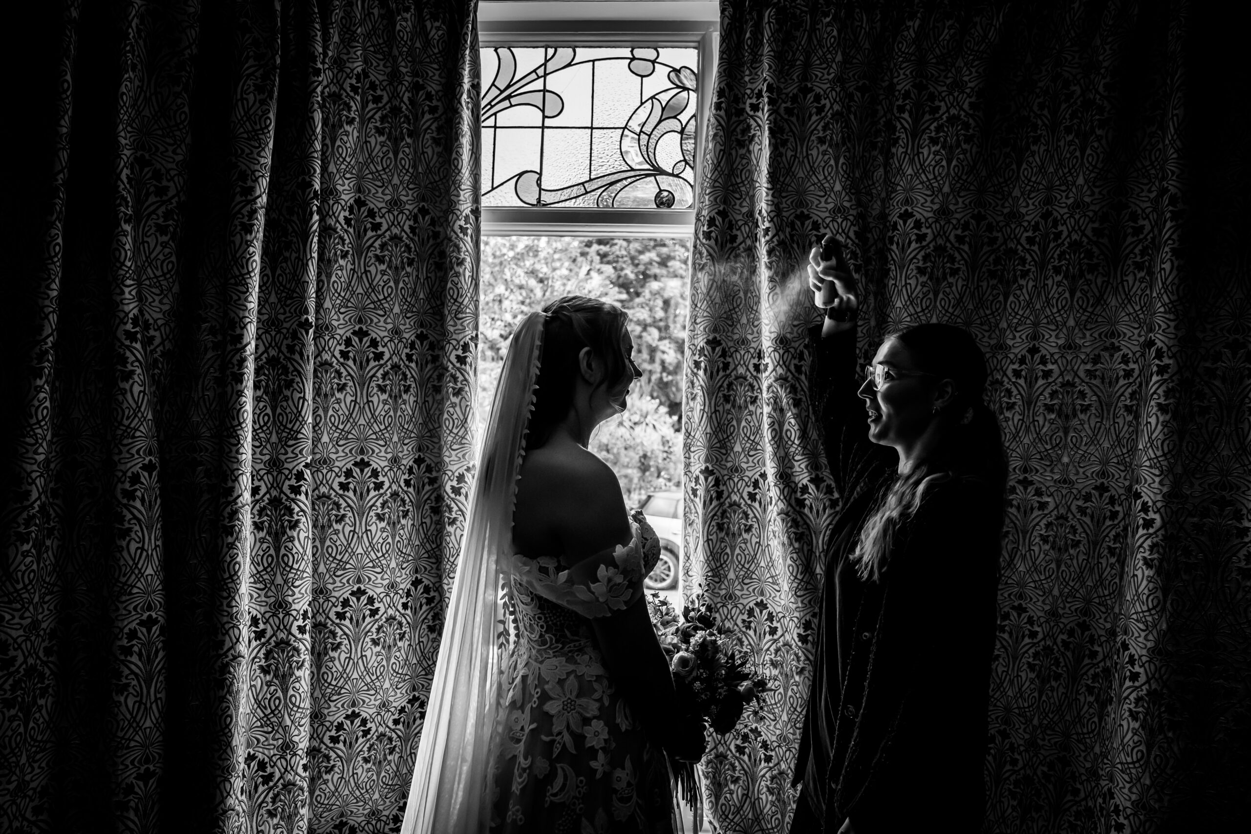 Silhouette of bride with stylist preparing