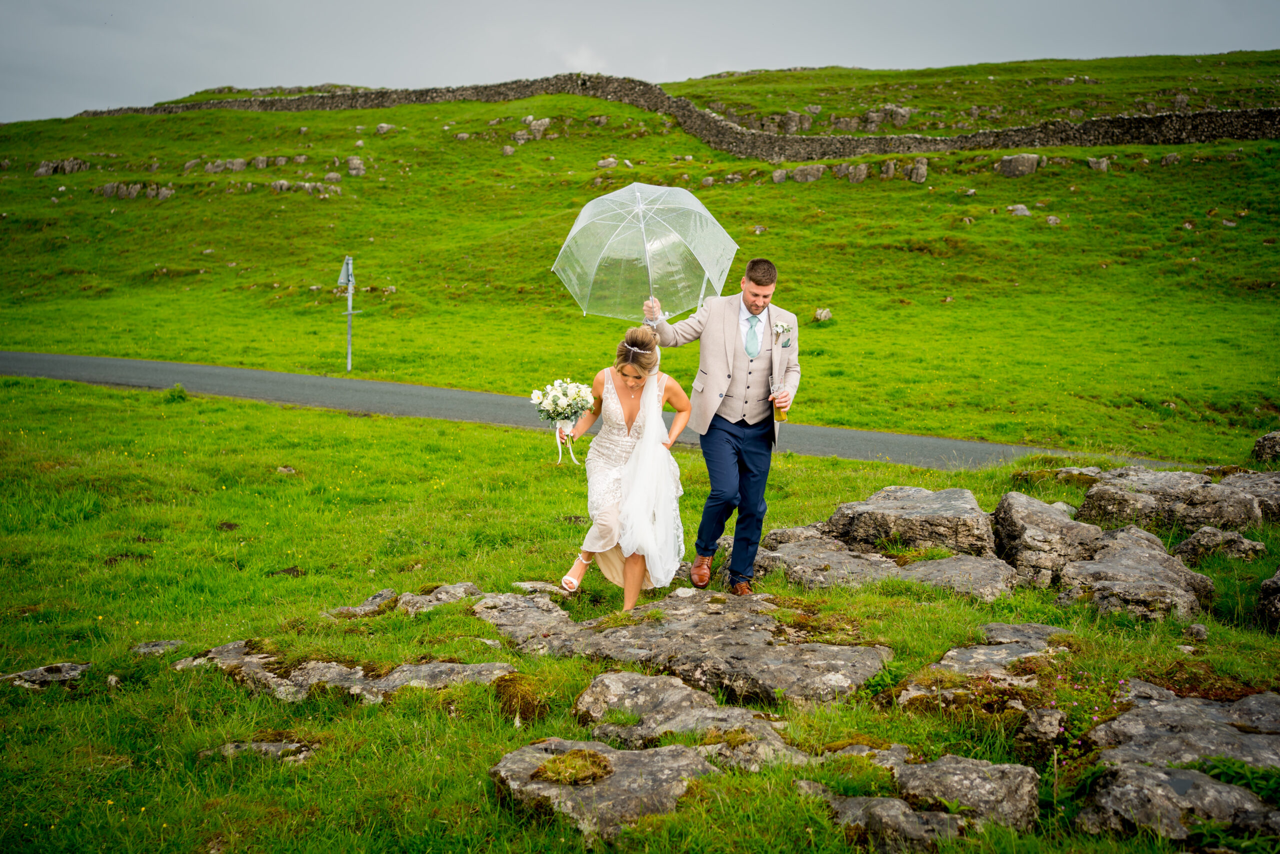 Bride and groom walking on grassy path.