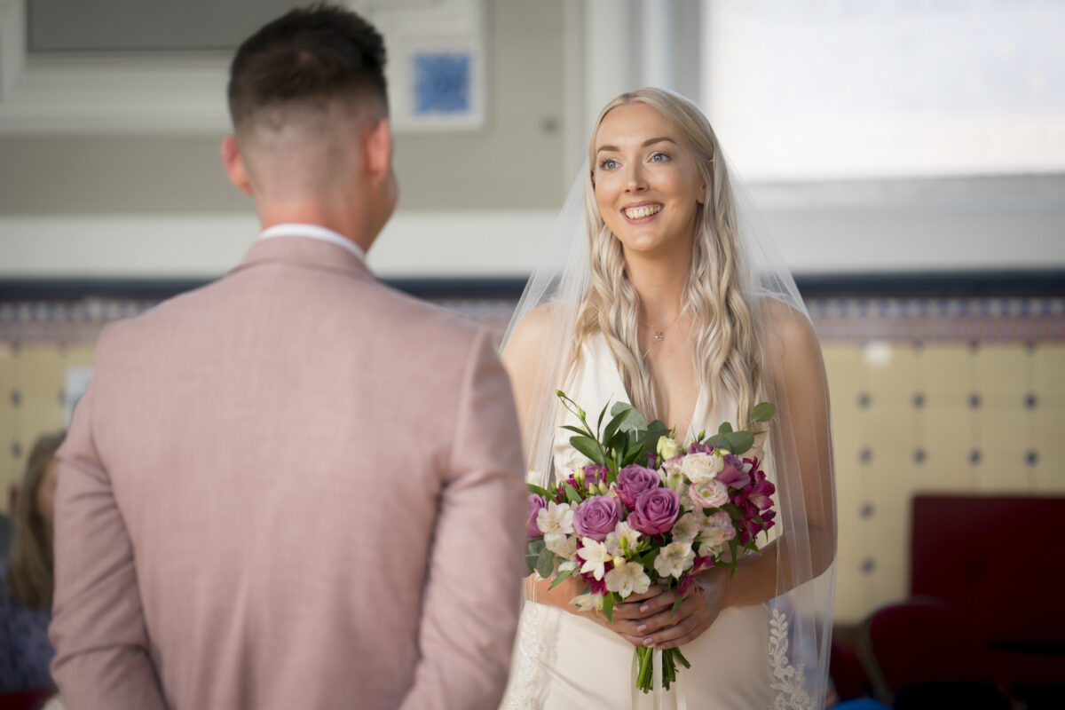 Bride smiling holding bouquet indoors
