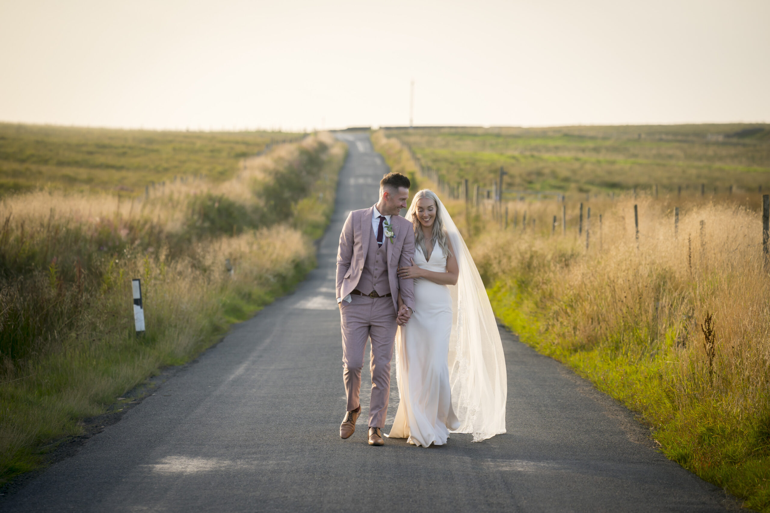 Bride and groom walking on country road