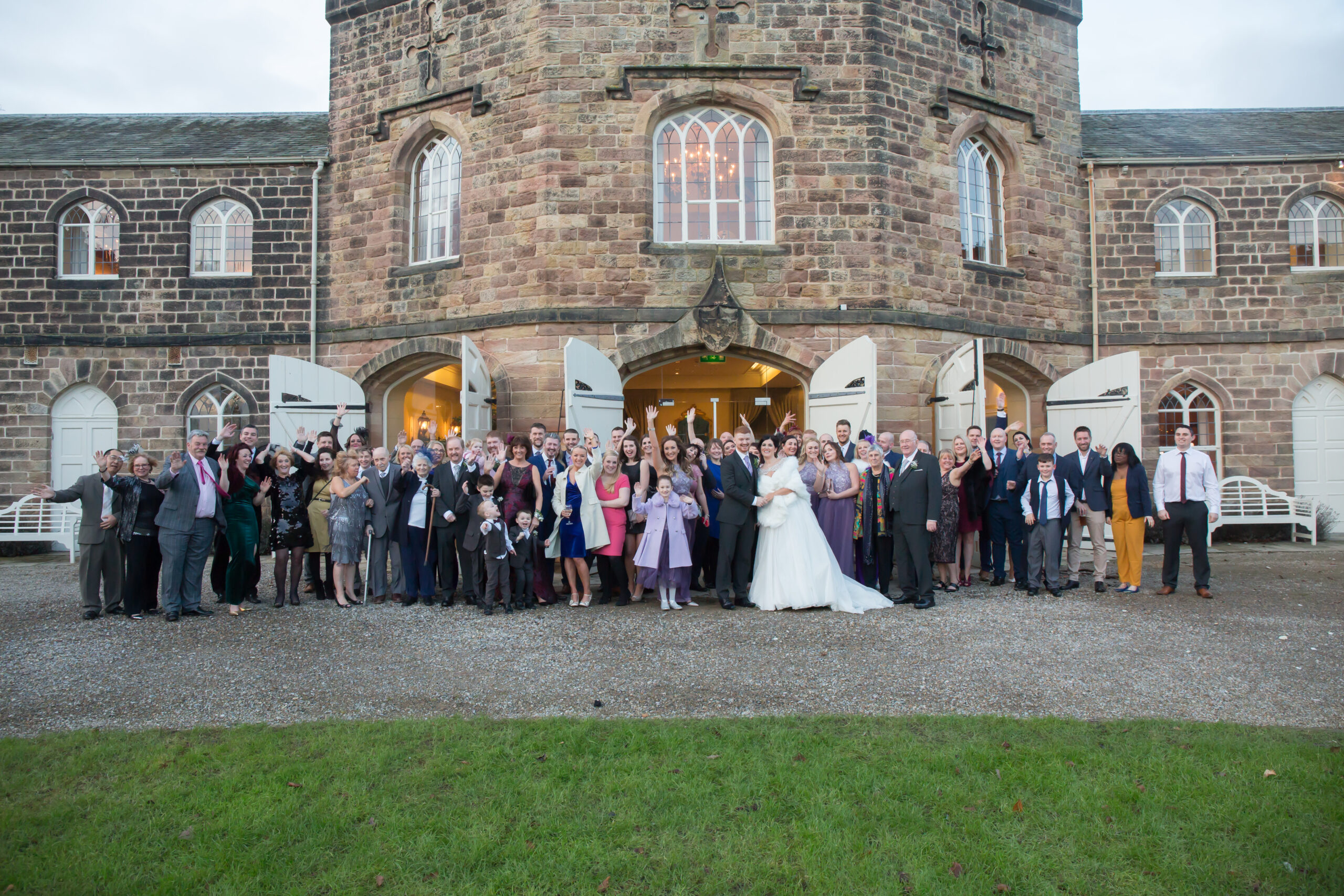 Large wedding group outside a historic building.