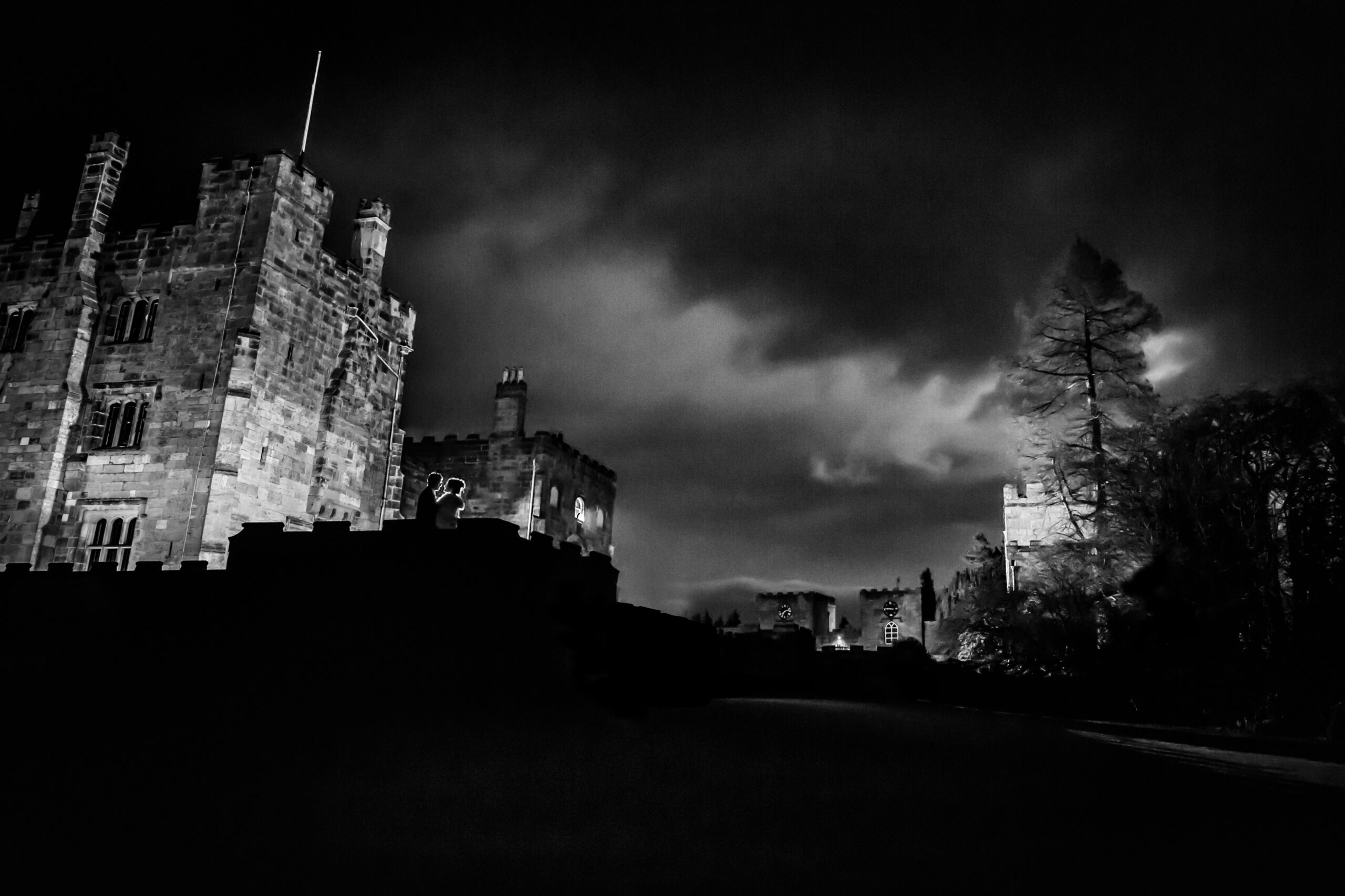 Silhouetted figures at a night-time castle.