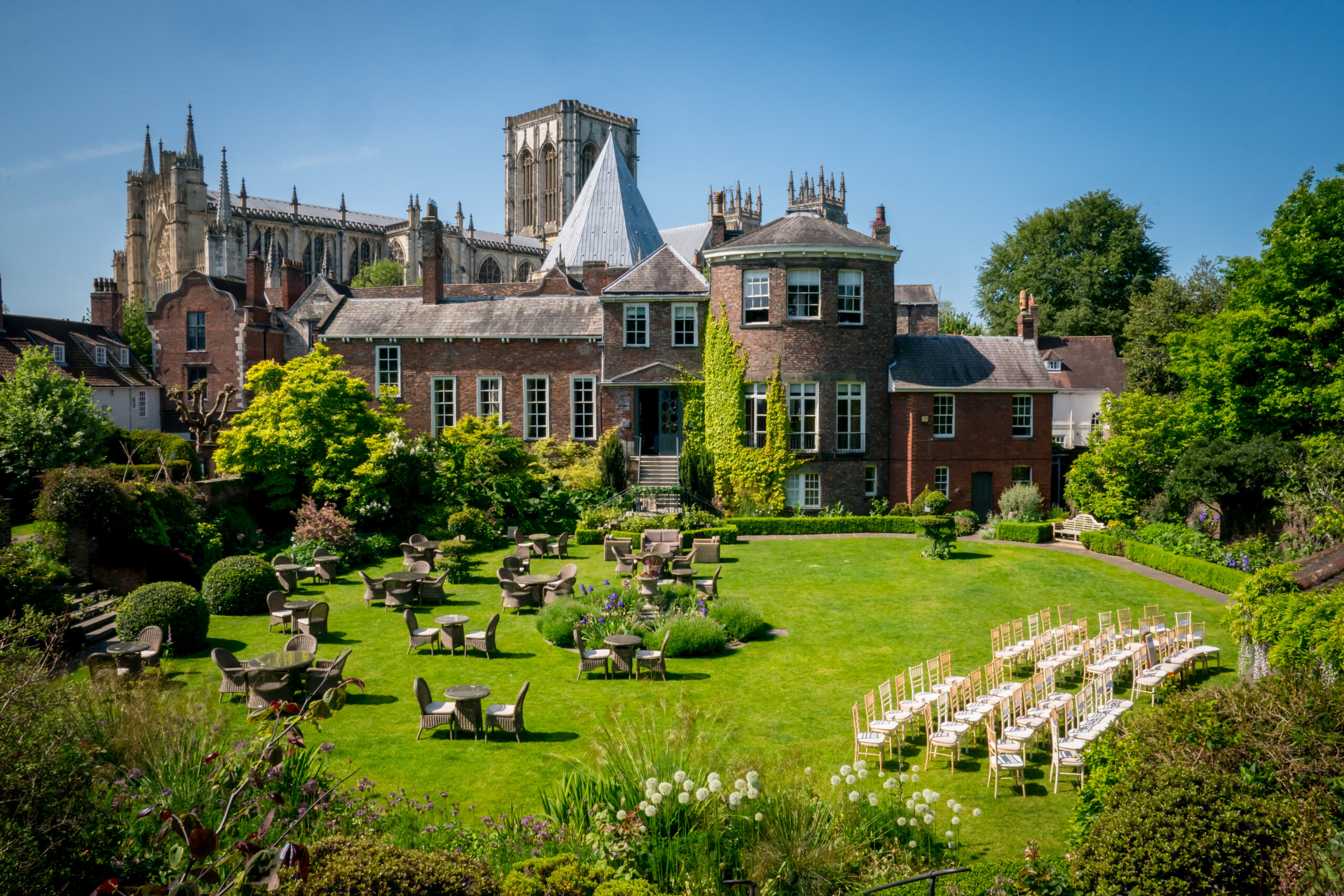 Historic building with lush garden and chairs.