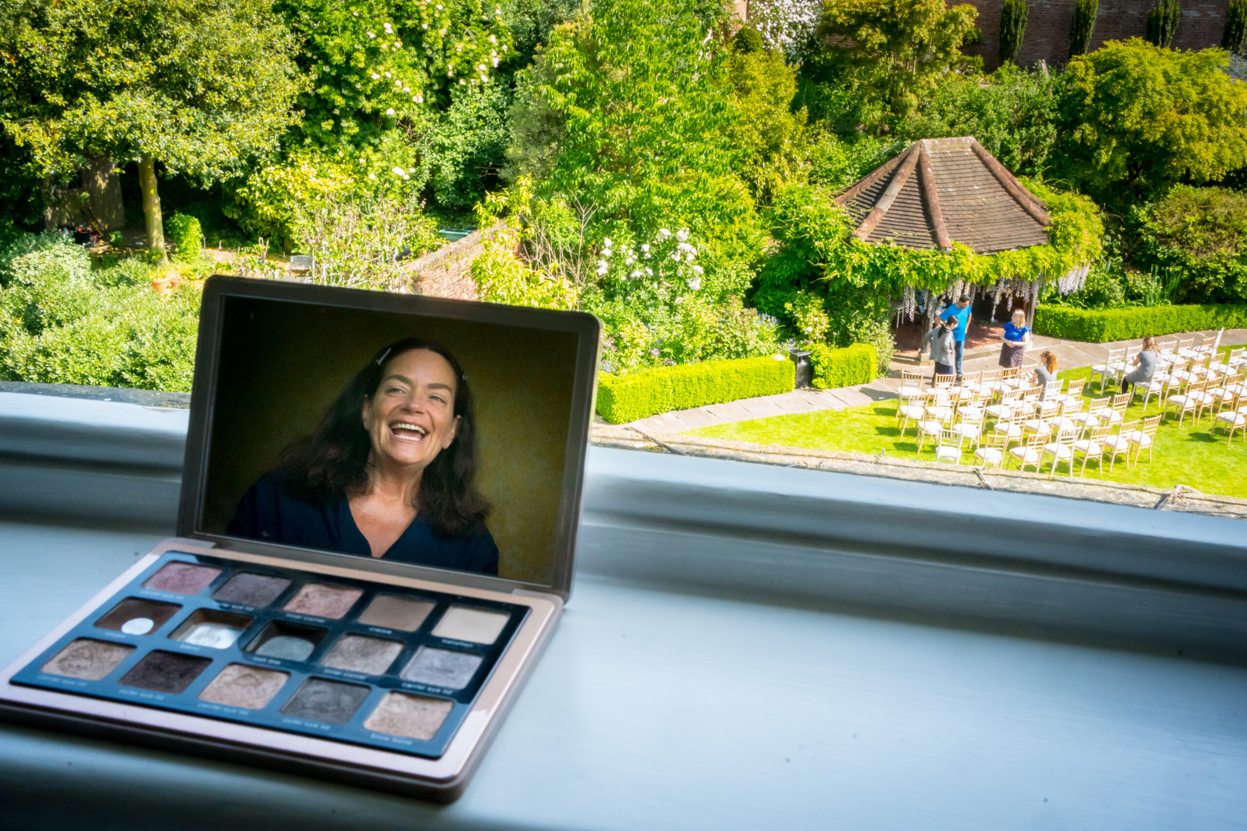 Open laptop facing a garden and event setup.