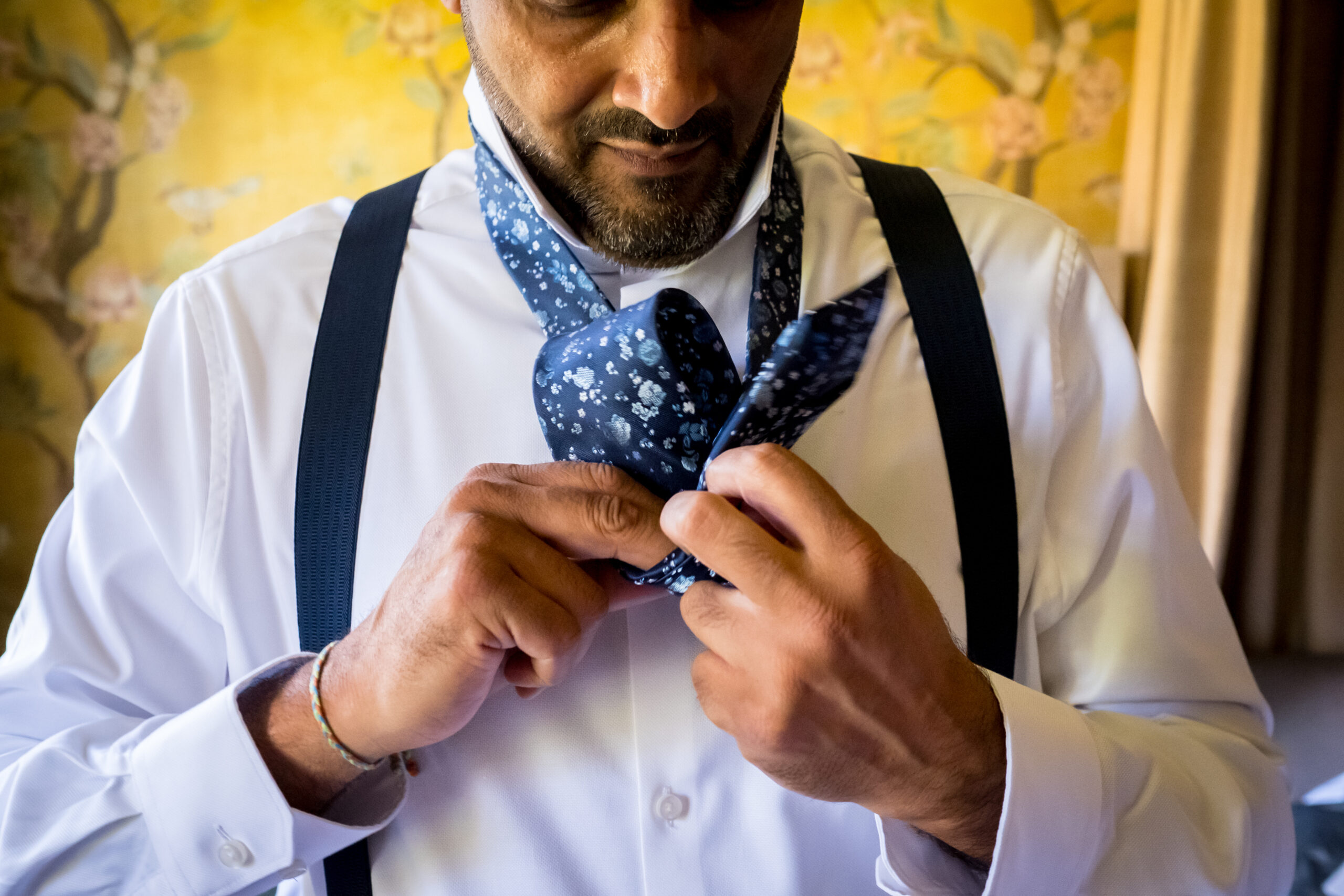 Man tying floral tie with braces