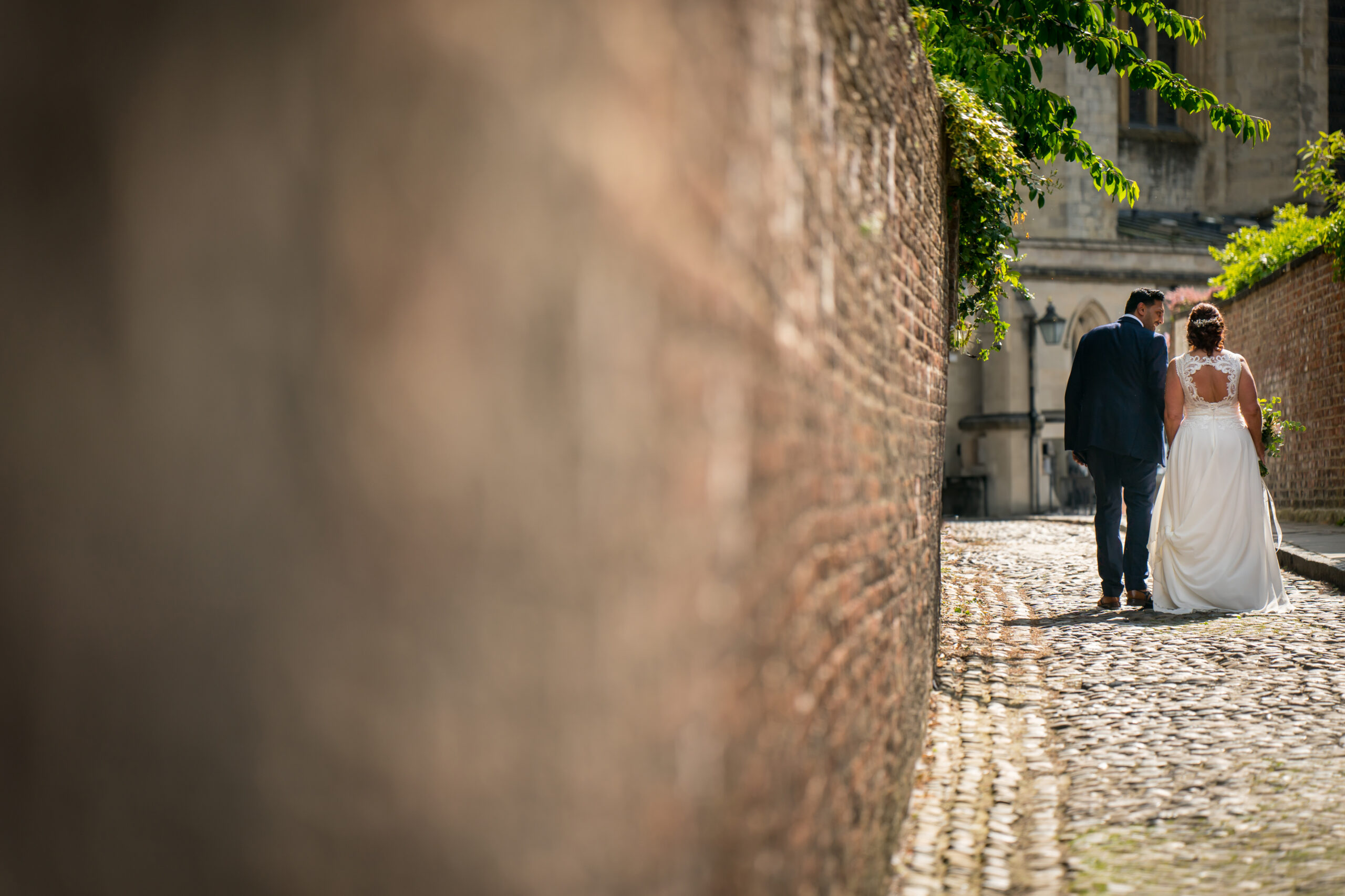Bride and groom walking down cobbled path