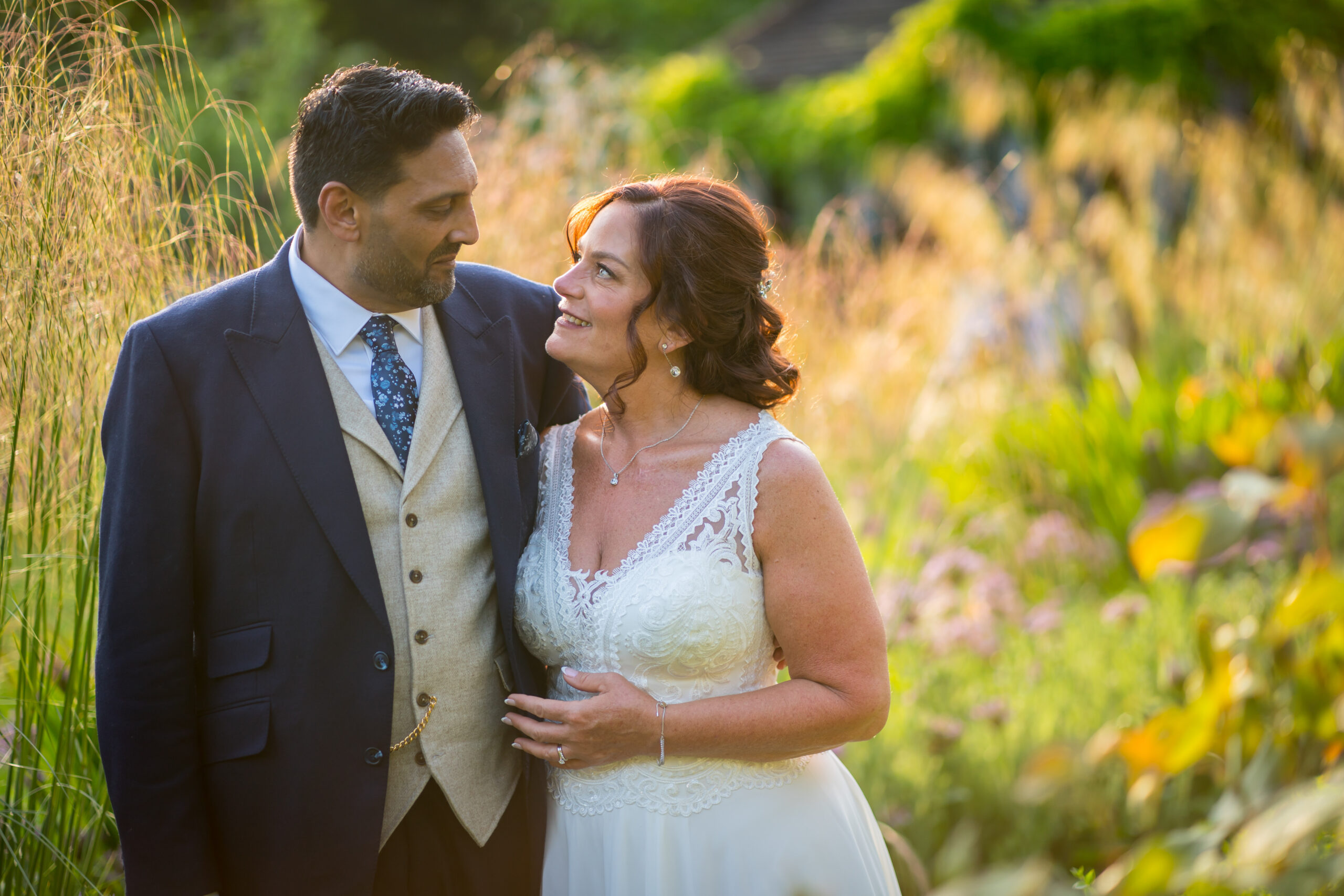 Couple smiling in a sunlit garden.