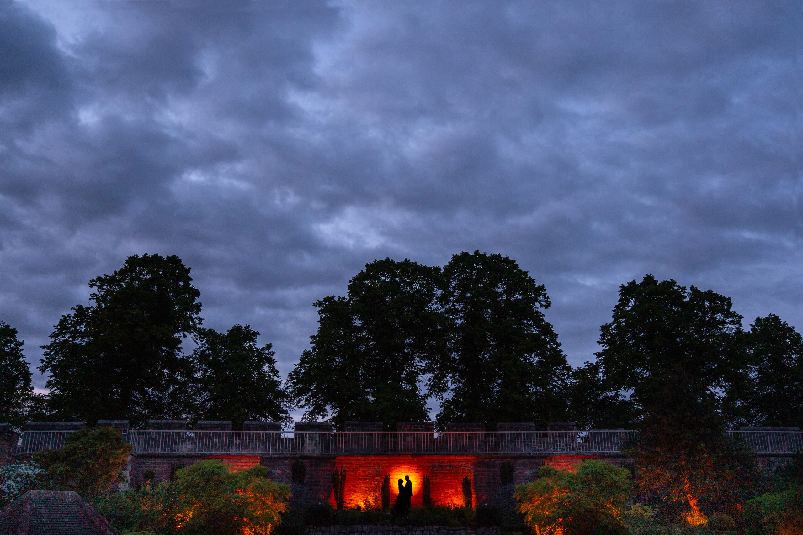 Silhouette of couple under dramatic evening sky.