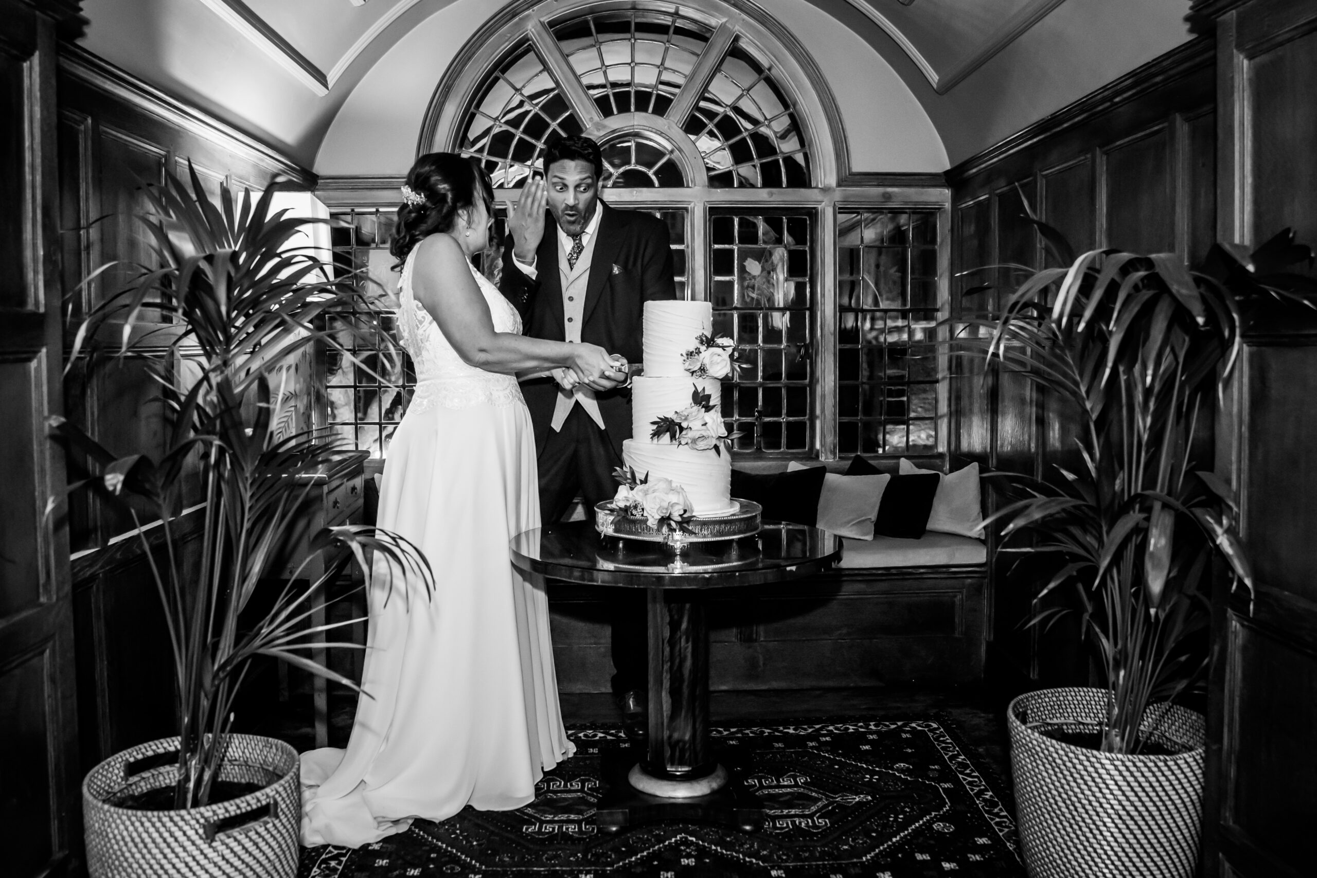 Couple cutting wedding cake indoors
