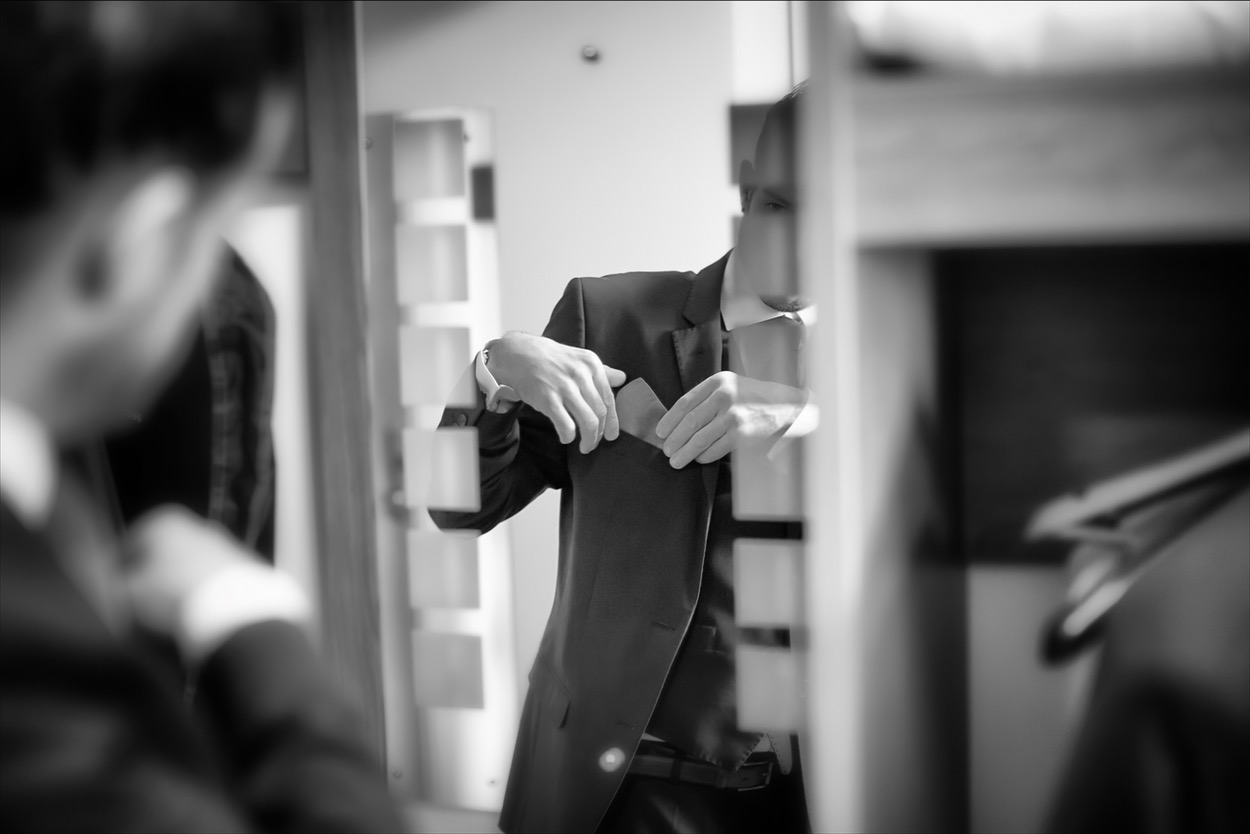 Man adjusting suit in a mirror