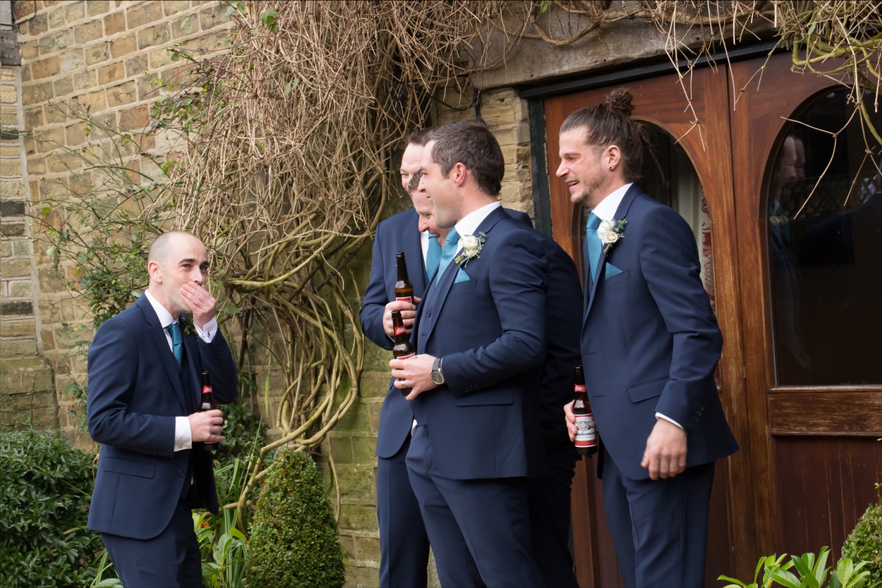 Groomsmen laughing and holding beer bottles