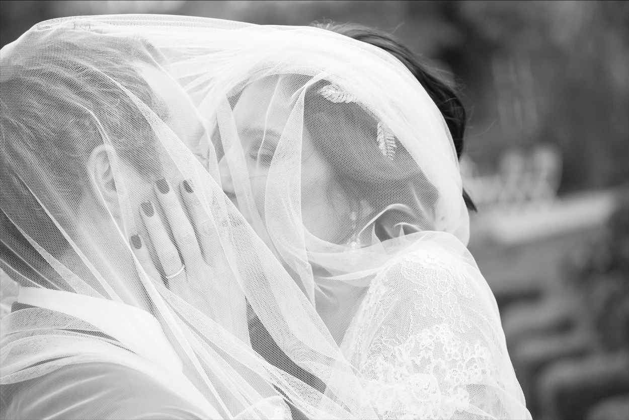 Bride and groom kissing under veil