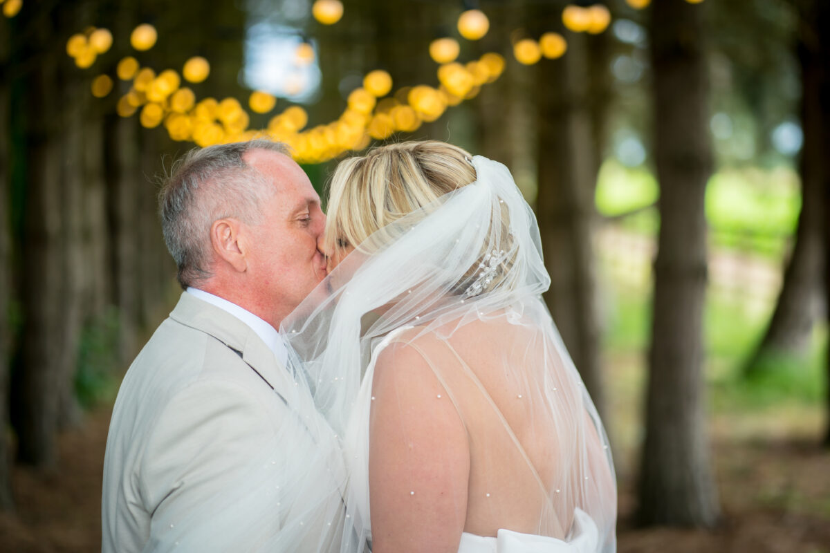 Bride and groom kissing under lights.