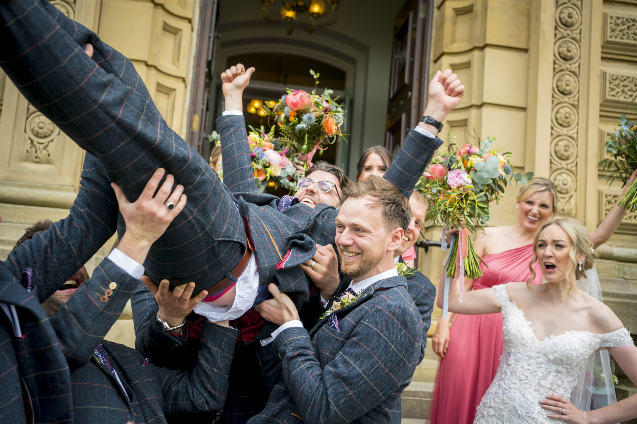 Wedding party lifting groom in celebration