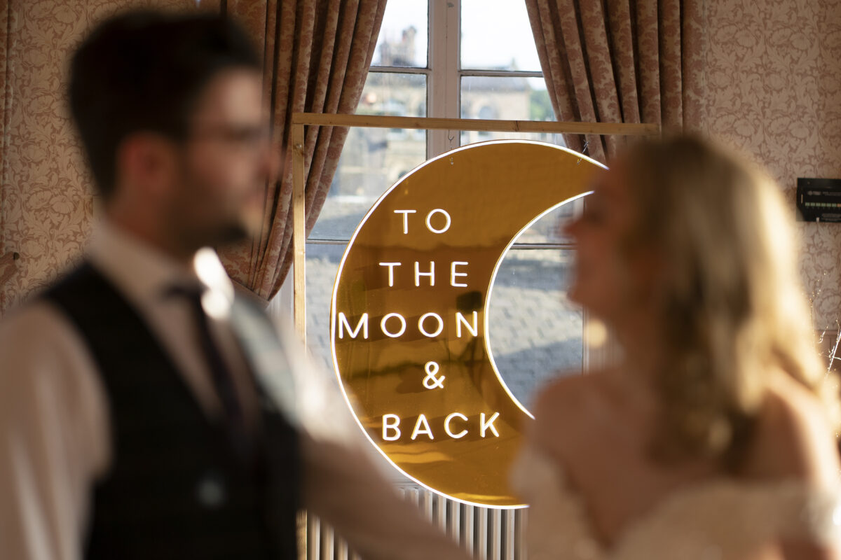 Couple with neon moon sign indoors