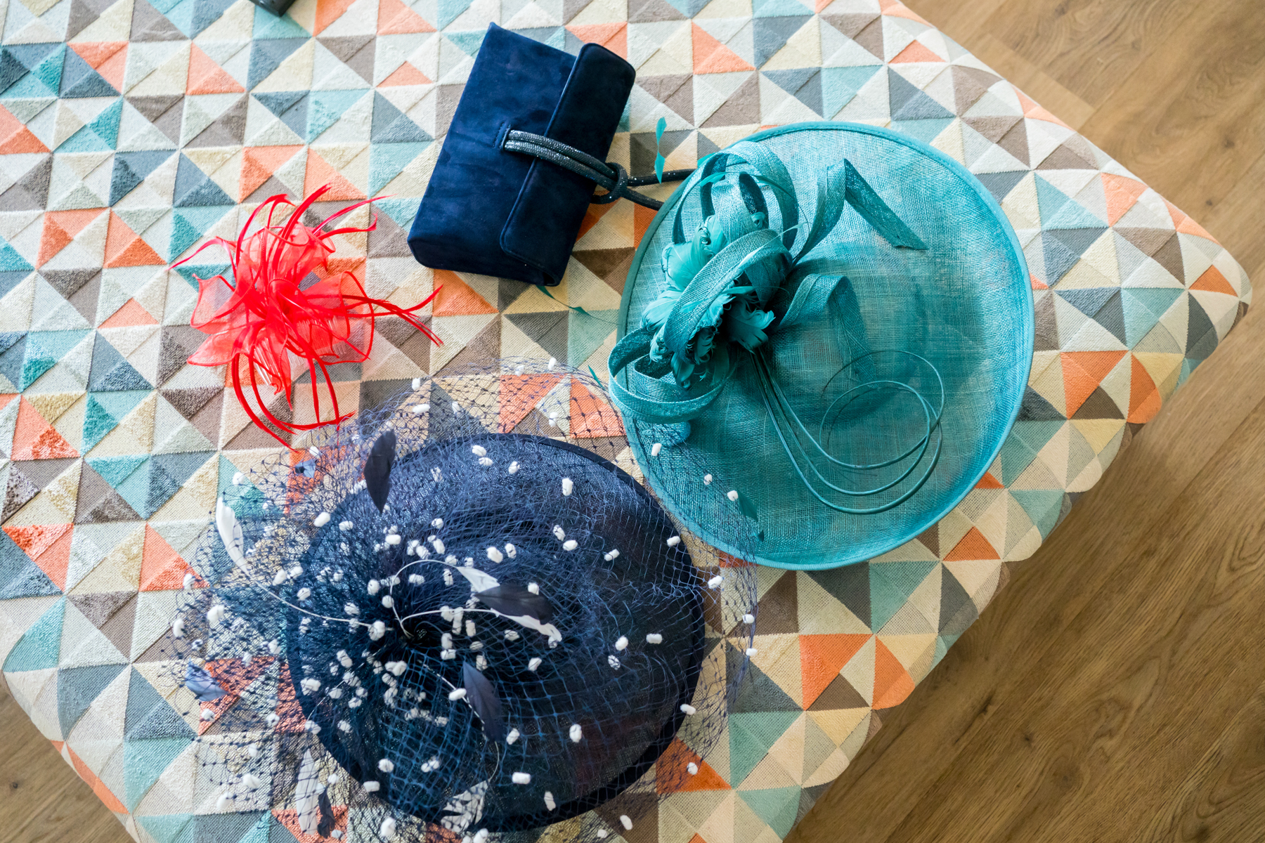 Colourful fascinators and navy clutch on patterned bench