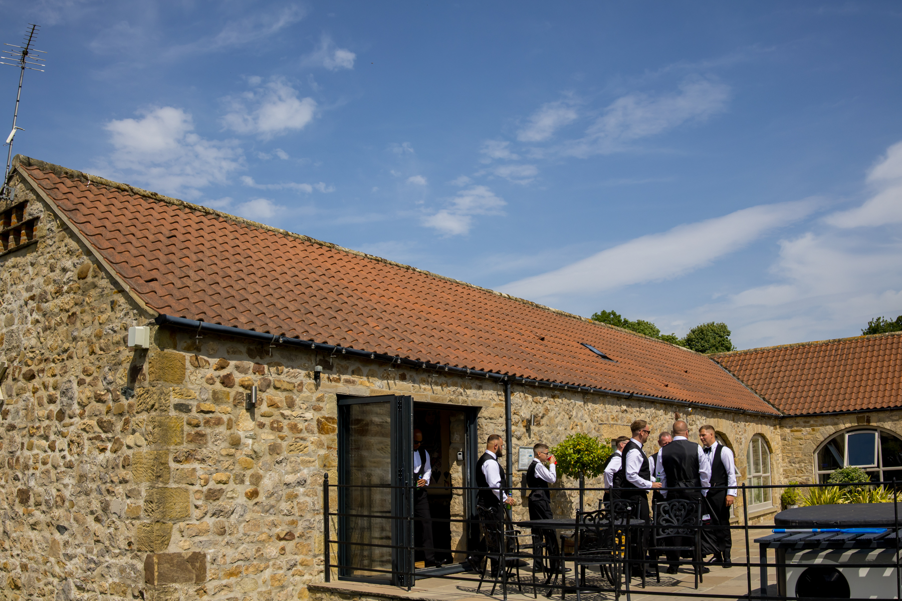 Men in suits outside stone barn venue