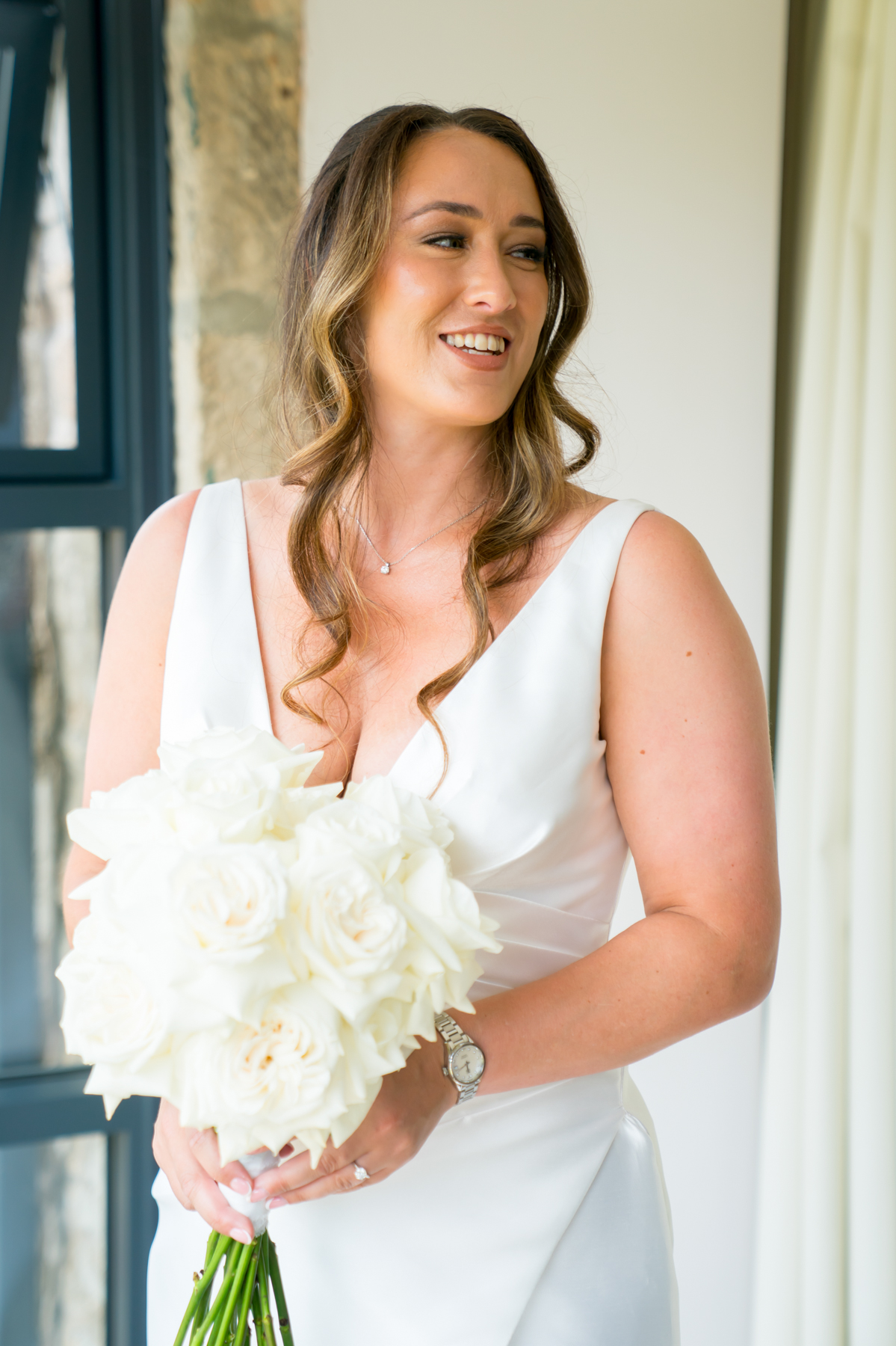 Bride holding white rose bouquet indoors