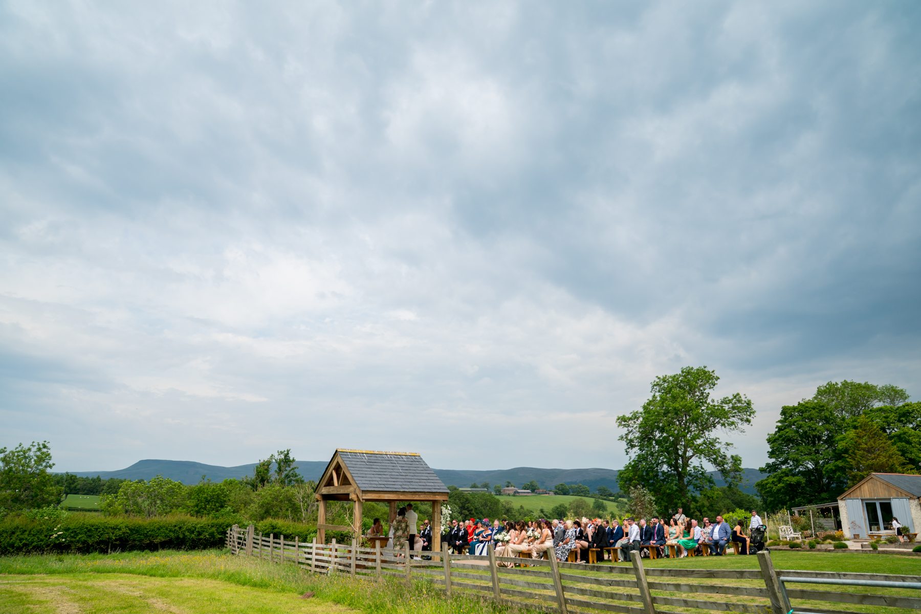 Outdoor countryside wedding ceremony with guests and gazebo