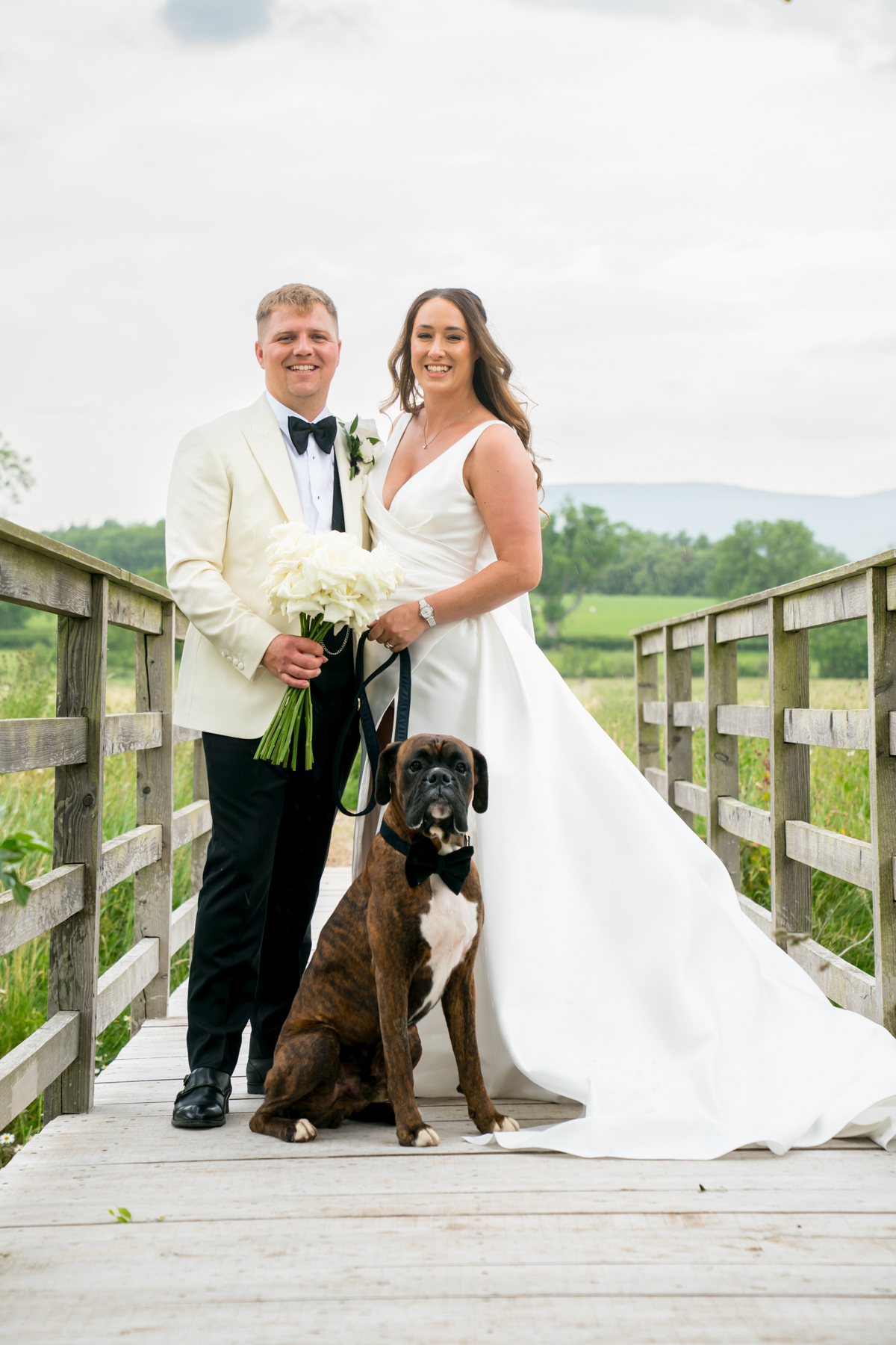 Bride and groom with dog on wooden bridge